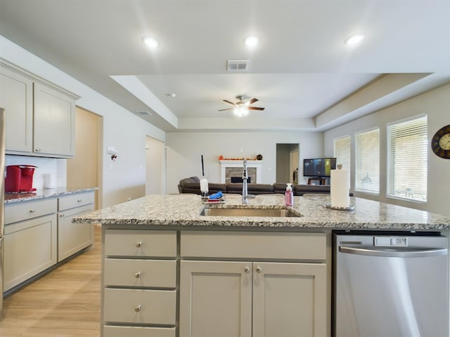 kitchen featuring sink, gray cabinetry, a tray ceiling, dishwasher, and an island with sink