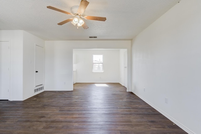 empty room featuring a textured ceiling, dark wood-type flooring, visible vents, and a ceiling fan