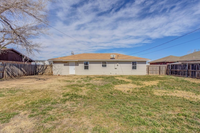 back of house with a fenced backyard and a yard