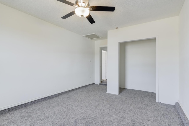 unfurnished bedroom featuring carpet floors, attic access, a ceiling fan, and a textured ceiling