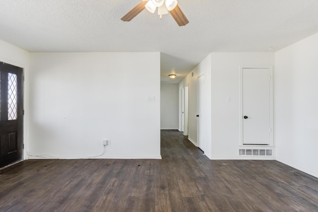 empty room featuring dark wood finished floors, visible vents, ceiling fan, a textured ceiling, and baseboards