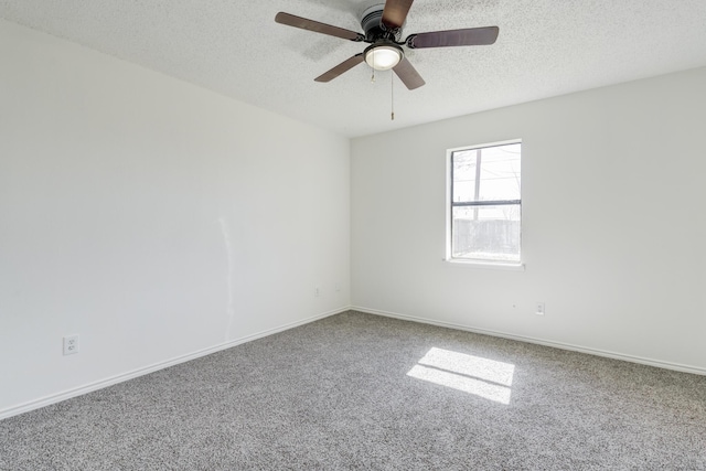 spare room with a textured ceiling, carpet, a ceiling fan, and baseboards