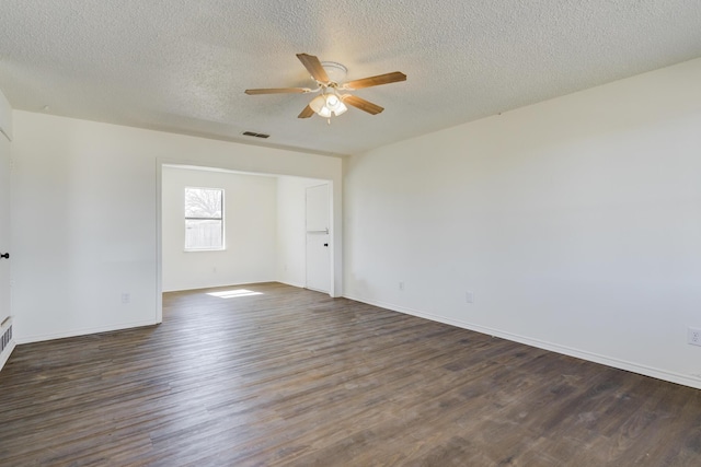 empty room with dark wood-style floors, visible vents, ceiling fan, a textured ceiling, and baseboards