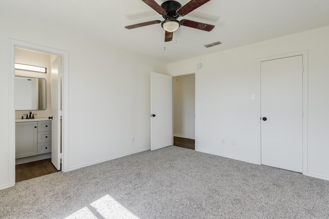 unfurnished bedroom featuring carpet floors, ensuite bath, visible vents, and baseboards