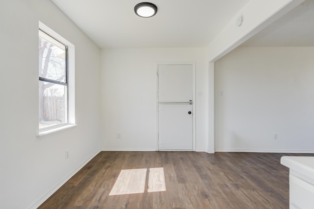 unfurnished room with dark wood-style flooring and baseboards