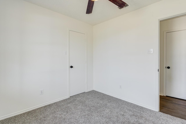 carpeted spare room with visible vents, ceiling fan, and baseboards