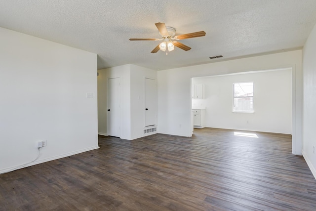 spare room with ceiling fan, visible vents, dark wood finished floors, and a textured ceiling