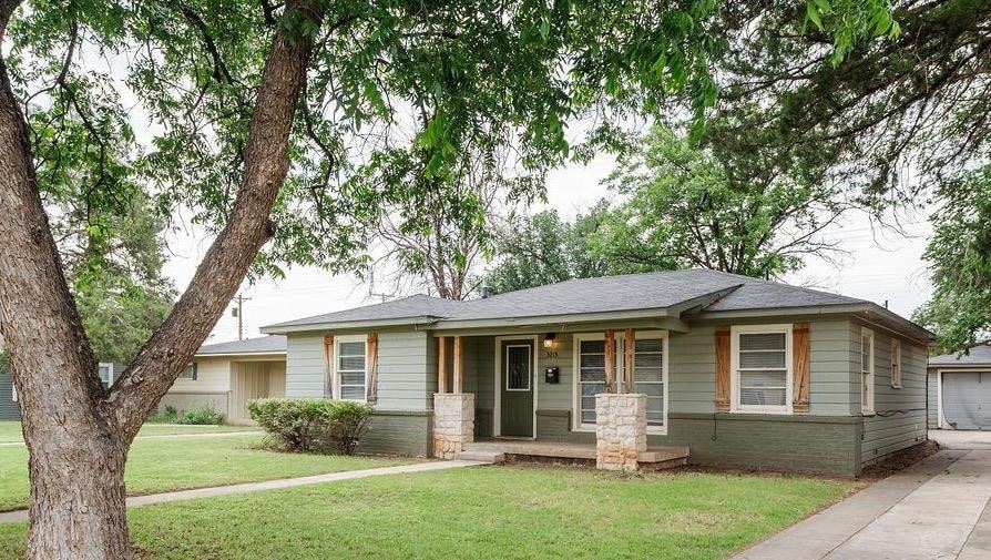 view of front of house featuring a garage, covered porch, and a front lawn