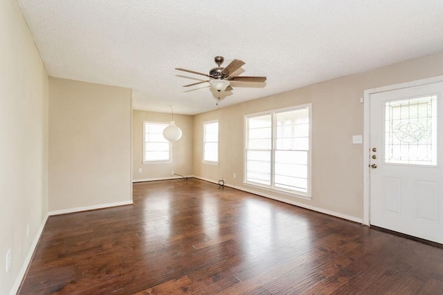 foyer entrance with ceiling fan, dark wood-type flooring, and a textured ceiling