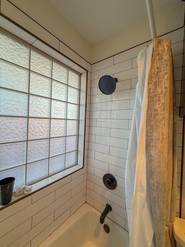 bathroom with a wealth of natural light and shower / tub combo with curtain