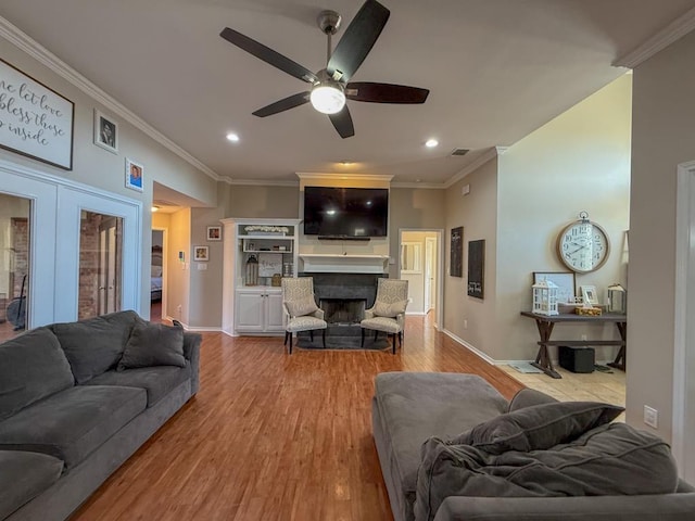 living room with ornamental molding, ceiling fan, and light wood-type flooring