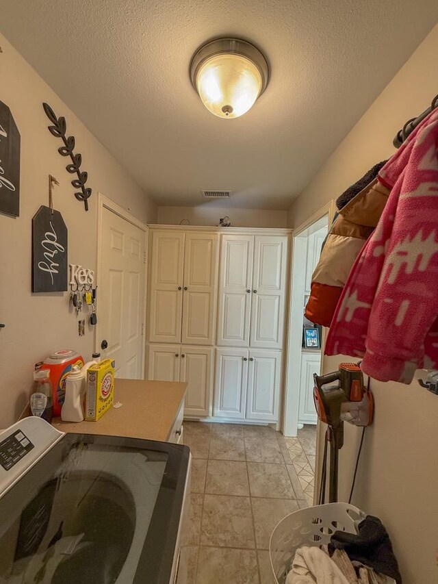 laundry area with cabinets, washer and dryer, and a textured ceiling