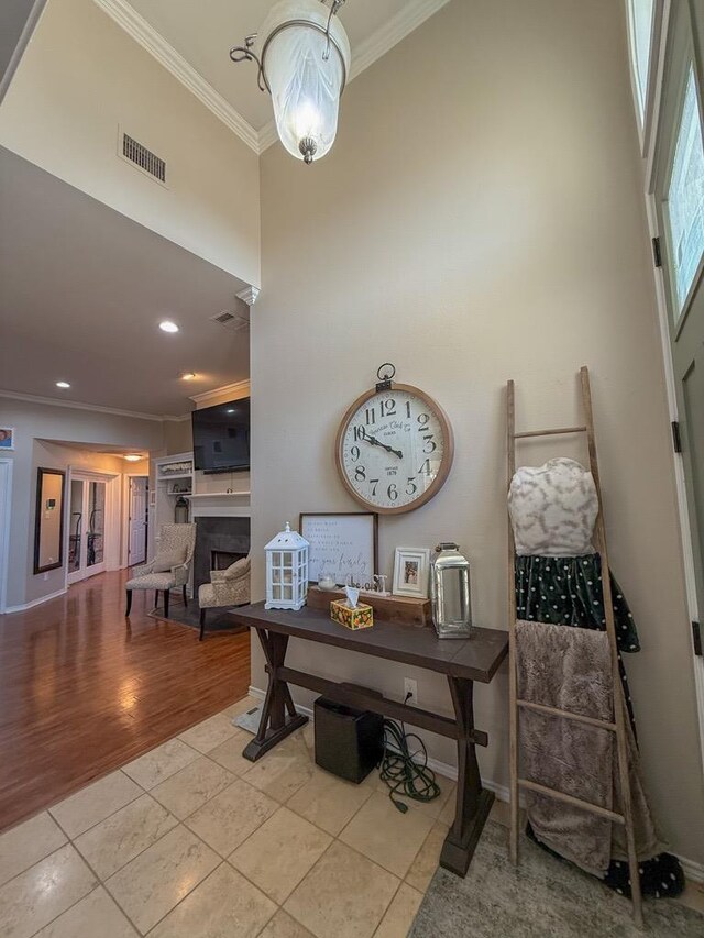 interior space featuring crown molding, light tile patterned flooring, and a high ceiling