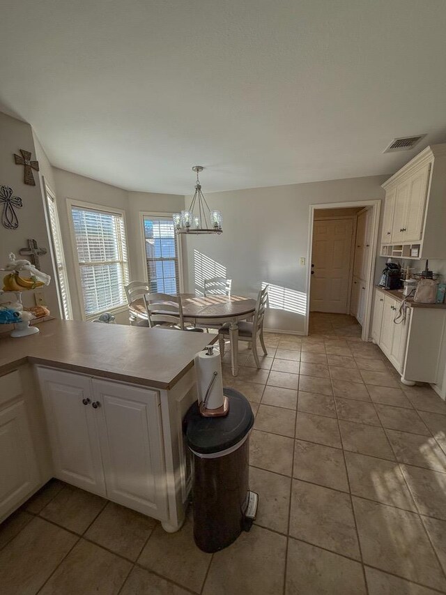 kitchen with white cabinetry, light tile patterned floors, decorative light fixtures, and kitchen peninsula