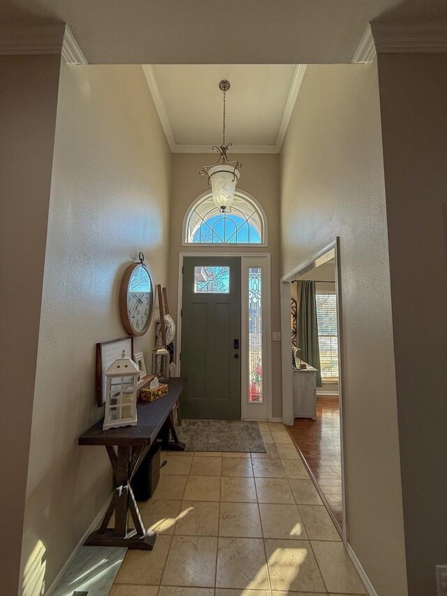 foyer entrance with ornamental molding and light tile patterned floors