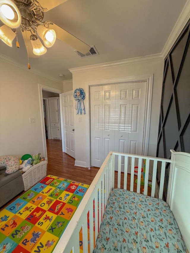 bedroom featuring crown molding, ceiling fan, wood-type flooring, and a closet