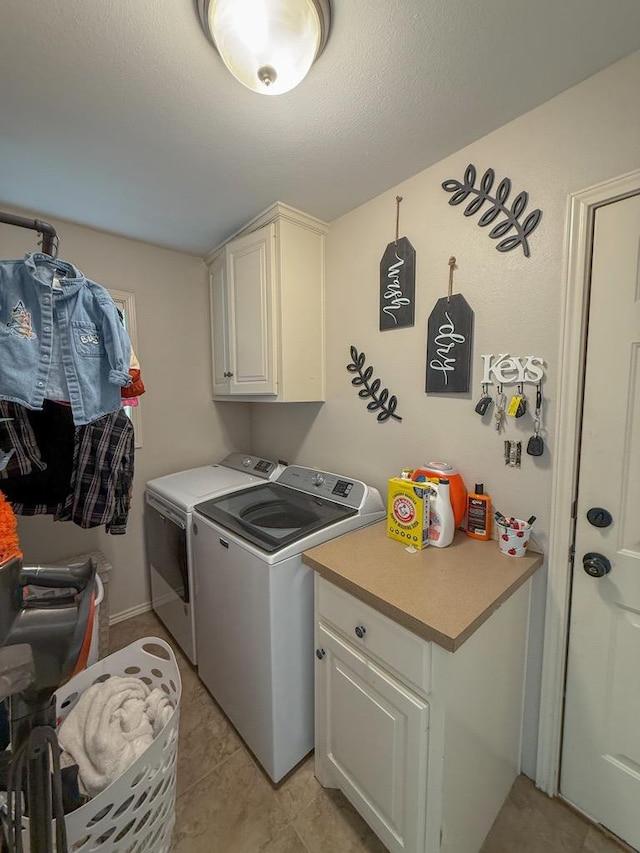 laundry area with a textured ceiling, cabinets, and washing machine and clothes dryer