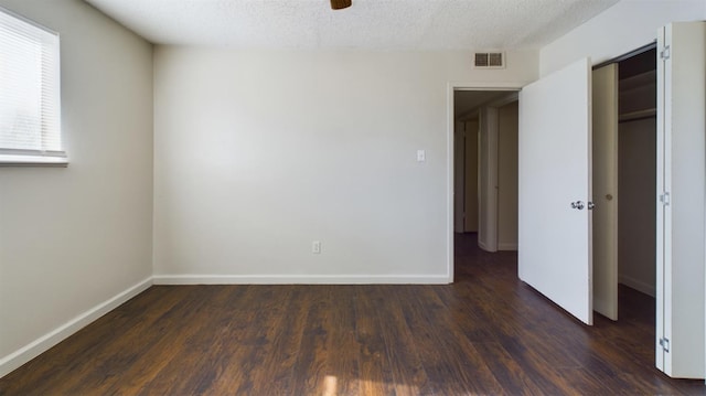 unfurnished room featuring dark wood-type flooring and a textured ceiling