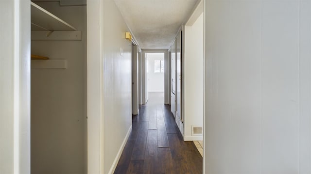 corridor featuring a textured ceiling and dark hardwood / wood-style flooring