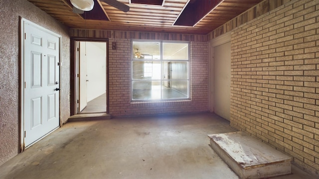 interior space with ceiling fan and brick wall