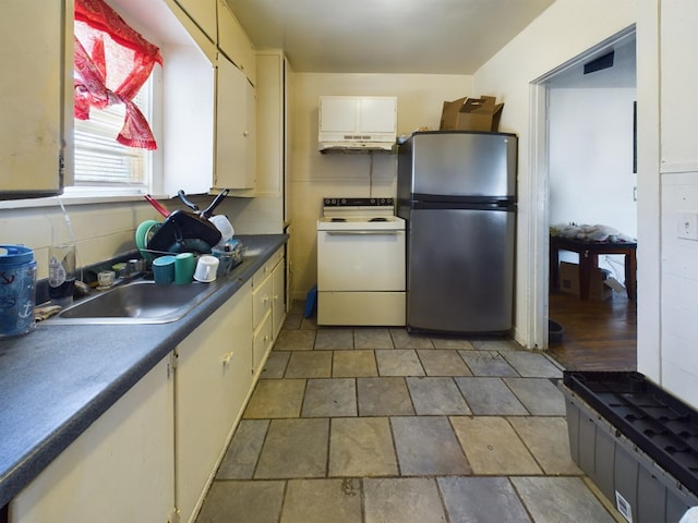 kitchen featuring white electric range, a sink, white cabinets, freestanding refrigerator, and dark countertops