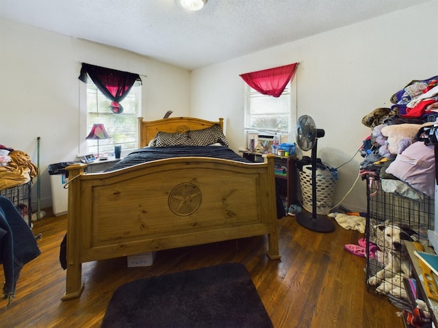 bedroom with a textured ceiling, multiple windows, and wood finished floors