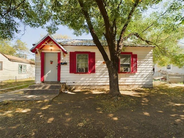 view of front of home featuring entry steps, metal roof, and fence