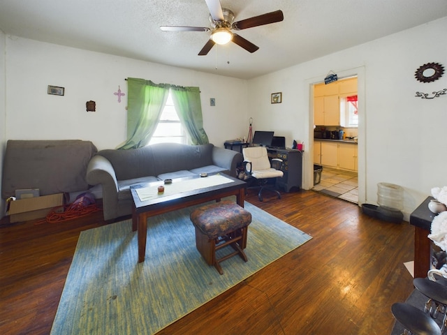 living room with ceiling fan, a textured ceiling, and wood finished floors