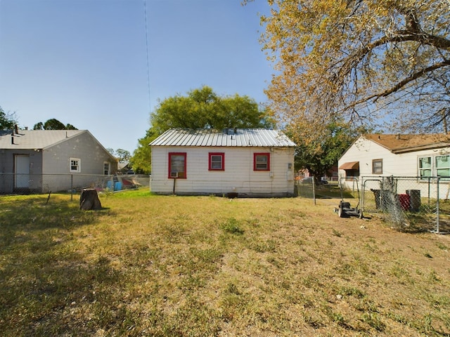 rear view of property featuring metal roof, a yard, and a fenced backyard