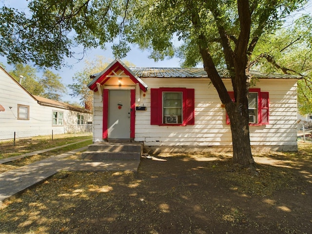 view of front of property featuring metal roof and fence