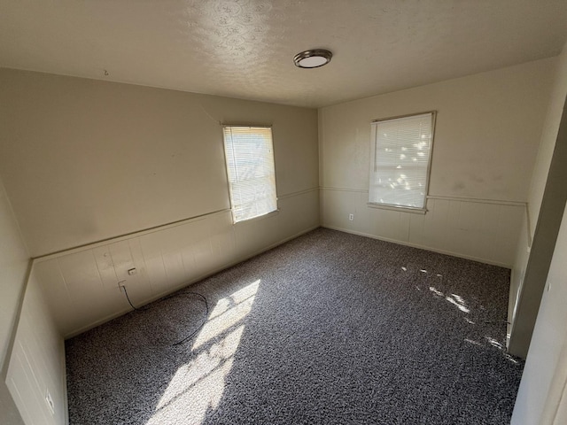 unfurnished room with dark carpet and a textured ceiling