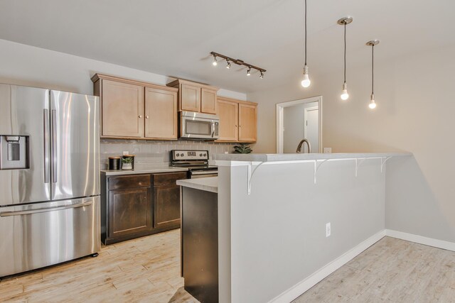 6205 21st St, Lubbock, TX 79407 - kitchen featuring appliances with stainless steel finishes, light wood-type flooring, light countertops, tasteful backsplash, and pendant lighting