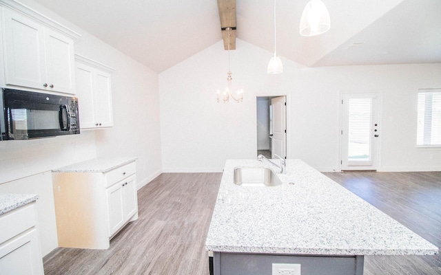 kitchen featuring white cabinetry, an island with sink, decorative light fixtures, and sink