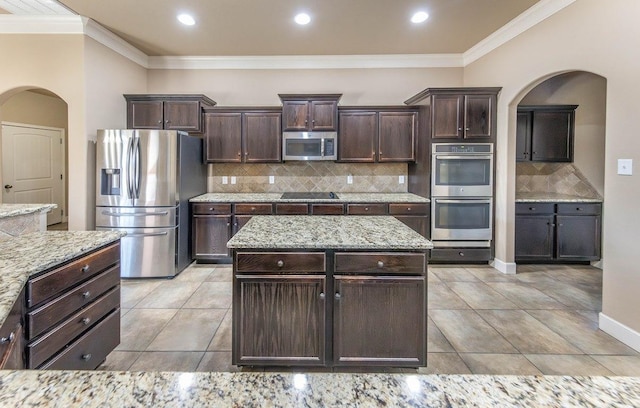 kitchen featuring dark brown cabinetry, stainless steel appliances, and backsplash