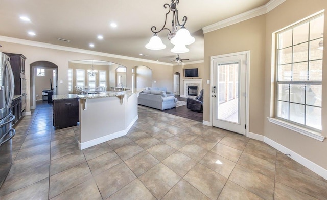 kitchen with pendant lighting, a center island, ornamental molding, light stone countertops, and a kitchen bar