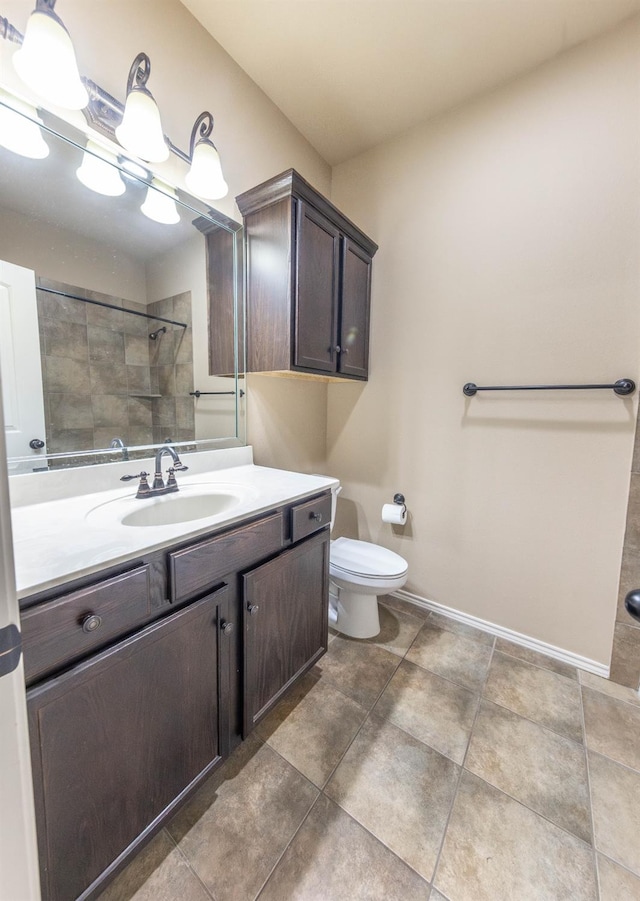 bathroom featuring vanity, a tile shower, and toilet