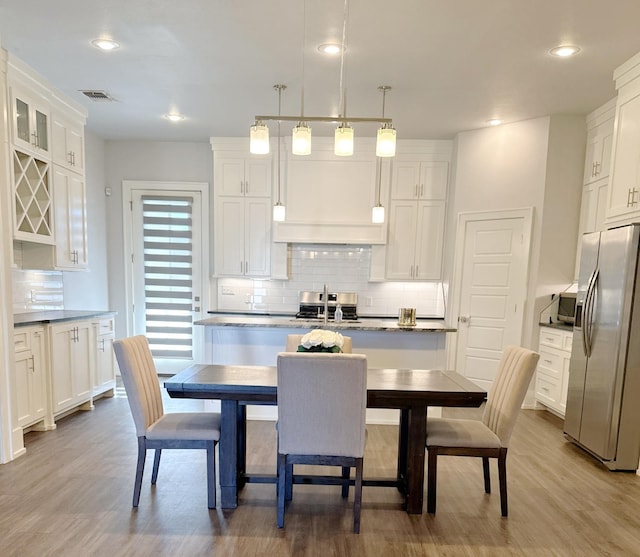 kitchen featuring pendant lighting, backsplash, stainless steel appliances, and white cabinets