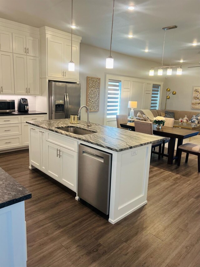 kitchen featuring pendant lighting, sink, appliances with stainless steel finishes, white cabinets, and a center island with sink