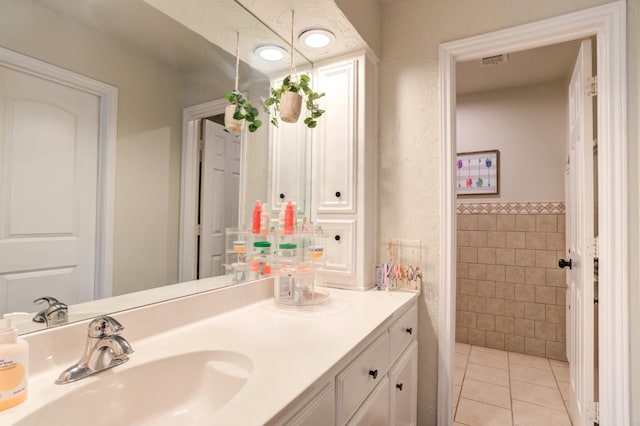 bathroom featuring tile patterned flooring, vanity, and tile walls