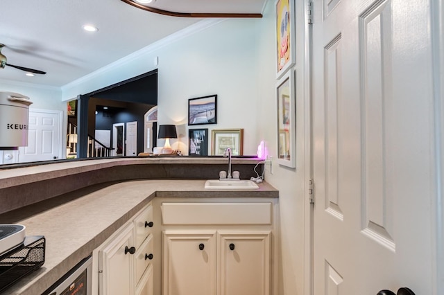 bar featuring sink, crown molding, and cream cabinets