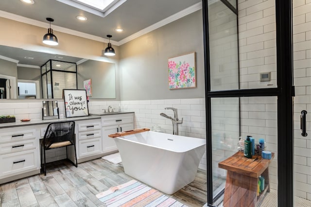 bathroom featuring tile walls, hardwood / wood-style floors, a skylight, vanity, and a bath