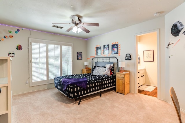 bedroom with light carpet, ensuite bath, and ceiling fan