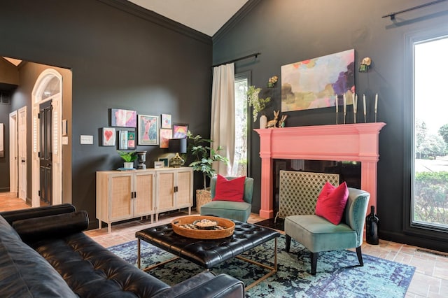 sitting room with high vaulted ceiling, crown molding, and a tile fireplace