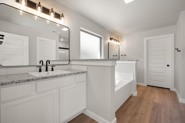 6811 54th St, Lubbock, TX 79407 - bathroom featuring vanity, wood-type flooring, and a bathing tub