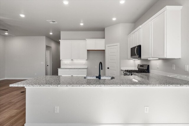 6811 54th St, Lubbock, TX 79407 - kitchen featuring sink, hardwood / wood-style flooring, light stone countertops, white cabinets, and stainless steel range with gas cooktop