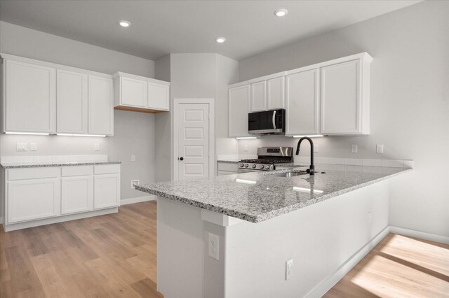 6811 54th St, Lubbock, TX 79407 - kitchen with sink, light stone counters, kitchen peninsula, stainless steel appliances, and white cabinets