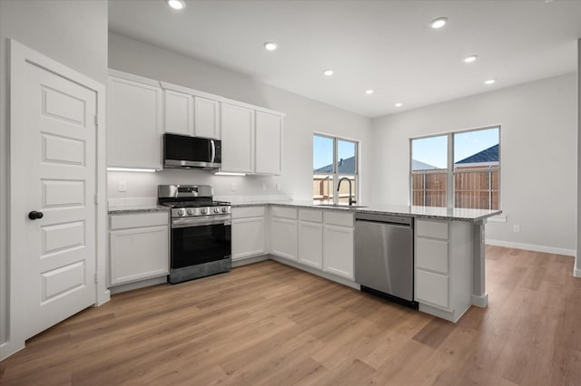 6811 54th St, Lubbock, TX 79407 - kitchen featuring light hardwood / wood-style flooring, light stone countertops, white cabinets, and appliances with stainless steel finishes