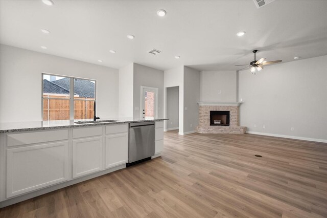 6811 54th St, Lubbock, TX 79407 - kitchen featuring sink, a brick fireplace, dishwasher, light stone countertops, and white cabinets