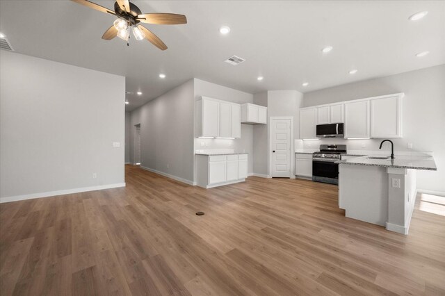 6811 54th St, Lubbock, TX 79407 - kitchen featuring sink, light hardwood / wood-style flooring, white cabinetry, stainless steel appliances, and light stone countertops