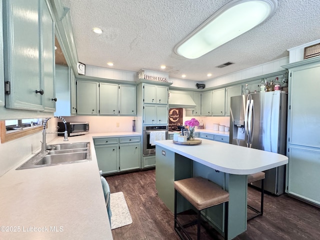 914 W Lee St, Floydada, TX 79235 - kitchen with a textured ceiling, appliances with stainless steel finishes, a kitchen island, dark wood-type flooring, and light countertops